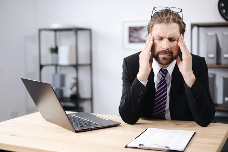 Empresario con dolor de cabeza sentado en la oficina