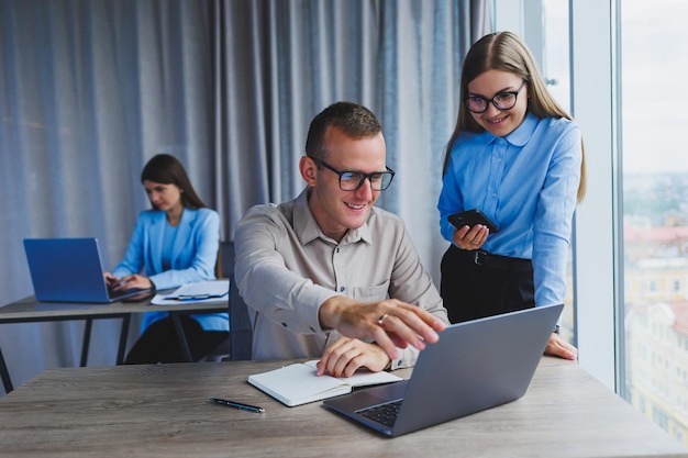 Empresário e colega trabalhando no escritório moderno no laptop Colegas no escritório estão conversando no trabalho e trabalhando em um novo projeto Pessoas de negócios no escritório