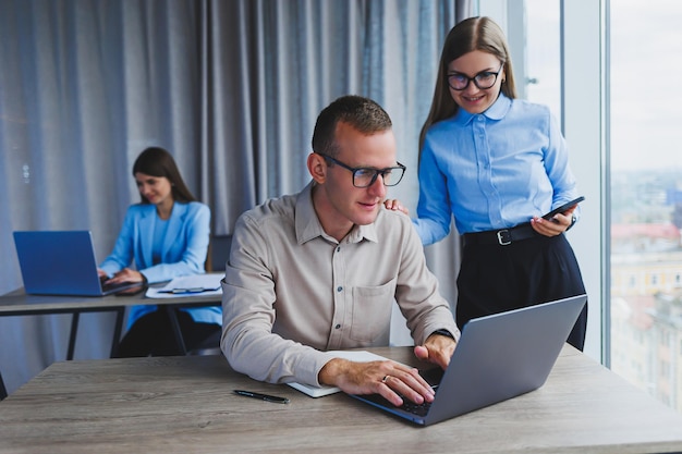 Empresário e colega trabalhando no escritório moderno no laptop Colegas no escritório estão conversando no trabalho e trabalhando em um novo projeto Pessoas de negócios no escritório