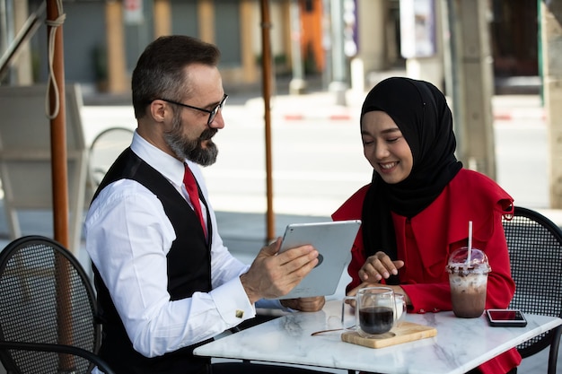 Empresário e empresária discutindo trabalho em um café