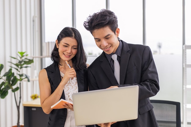 Empresário e empresária reunidos discutindo e trabalhando em conjunto com o laptop