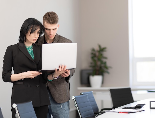 Empresário e empresária reunidos em escritório moderno trabalhando em reunião de negócios de laptop