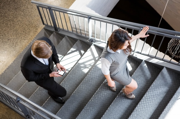 Empresário e empresária subir escada no escritório