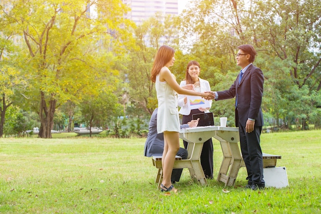 empresário e mulher apertando as mãos no jardim.