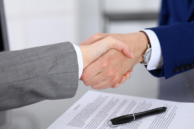 Empresário e mulher de negócios apertando as mãos um ao outro acima do contrato assinado