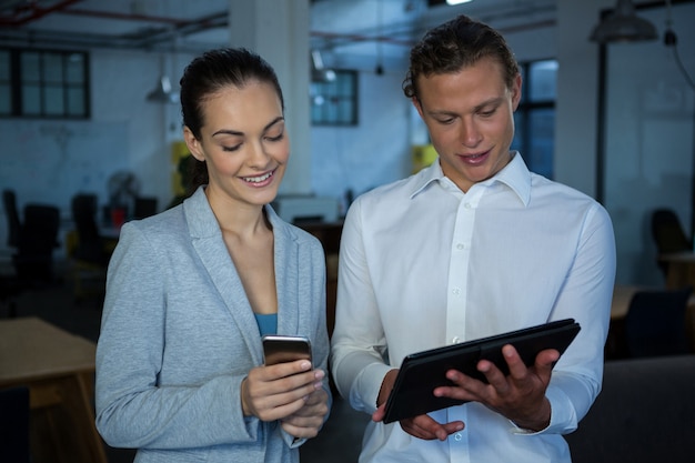 Empresário e um colega discutindo sobre tablet digital e telefone celular