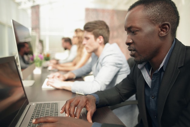 Empresário e um grupo de funcionários trabalhando na sala de informática