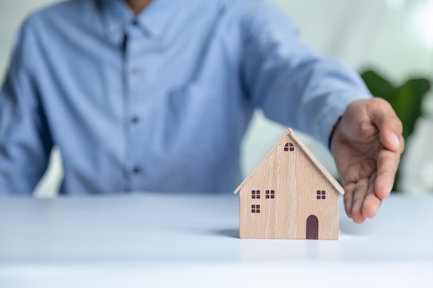 Empresario eligiendo el modelo de mini casa de madera del modelo en la mesa de madera Planificación para comprar el concepto de propiedad Elija lo mejor