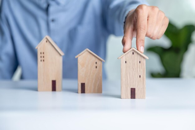 Empresario eligiendo el modelo de mini casa de madera del modelo en la mesa de madera Planificación para comprar el concepto de propiedad Elija lo mejor