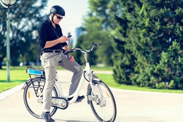 Empresário em bicicleta elétrica usando telefone celular