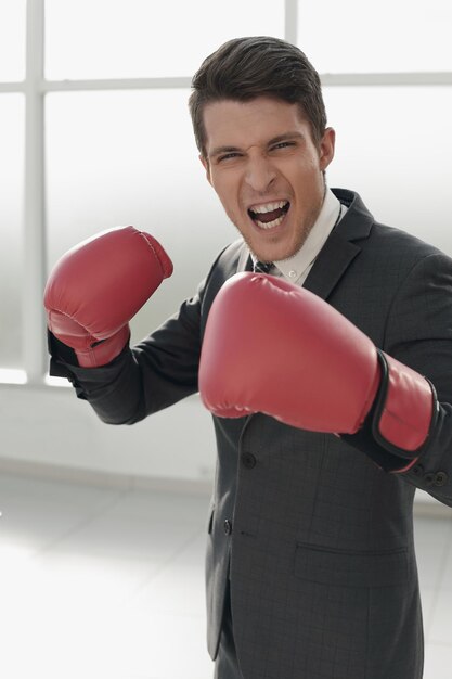 Foto empresário em luvas de boxe em pé perto da janela do escritório conceito de competitividade