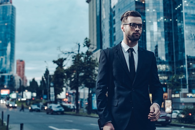 Empresário em movimento. Imagem noturna de homem jovem e bonito confiante em traje completo