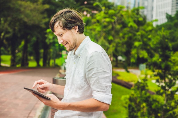 Empresário em roupas casuais usando tablet no parque