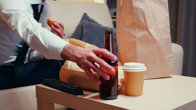 Empresário em sua casa descansando e bebendo cerveja. Alimentos não saudáveis