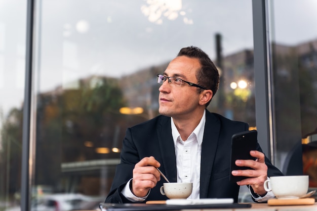 Empresário em um café usando um smartphone