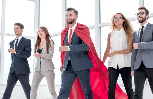 Foto empresário em um manto vermelho marchando com a equipe de negócios