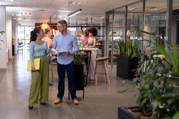 Foto empresario y empresaria birracial discutiendo mientras se encuentra en un lugar de trabajo moderno