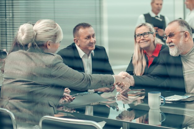 empresario y empresaria dándose la mano sobre la mesa de negociaciones. el concepto de cooperación