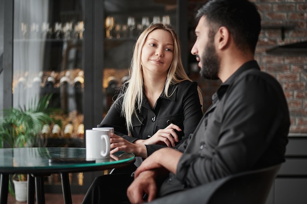 Empresario y empresaria hablando sentado en una mesa en un café