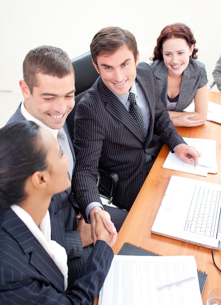 Foto empresario y empresaria en una reunión dándose la mano