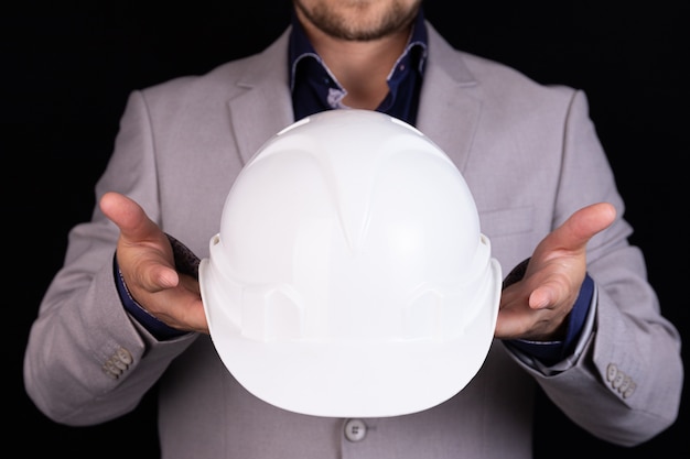 Foto empresário, engenheiro civil, segurando um capacete branco nas mãos