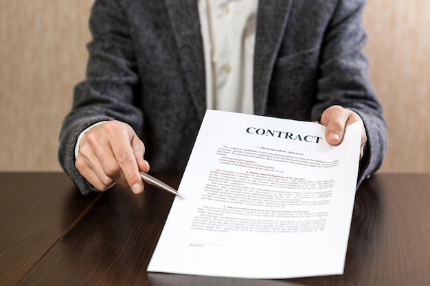 El empresario entrega un contrato para la firma ofreciendo un bolígrafo en la mano