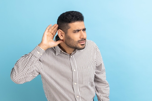 Empresario entrometido con barba sosteniendo la mano cerca de la oreja escuchando conversaciones interesantes y secretos privados