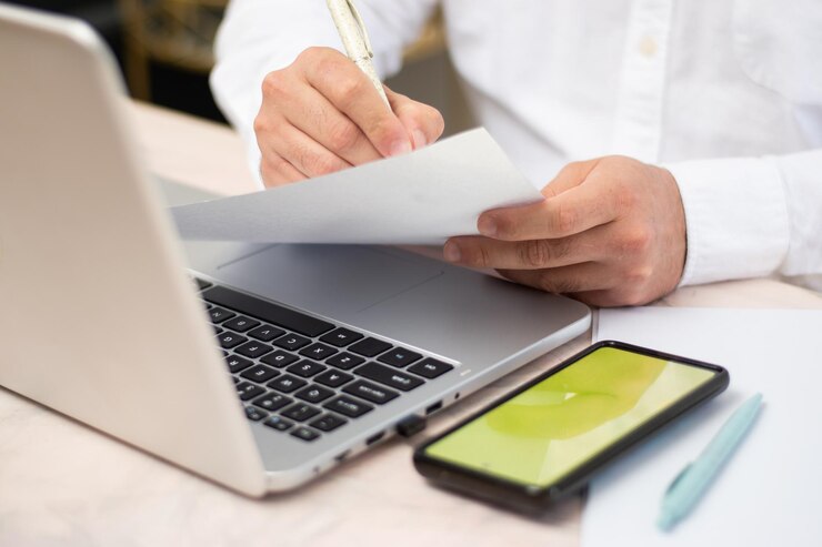 Foto empresário escrevendo em um lençol branco na frente de seu laptop e um telefone celular com chroma key no próximo