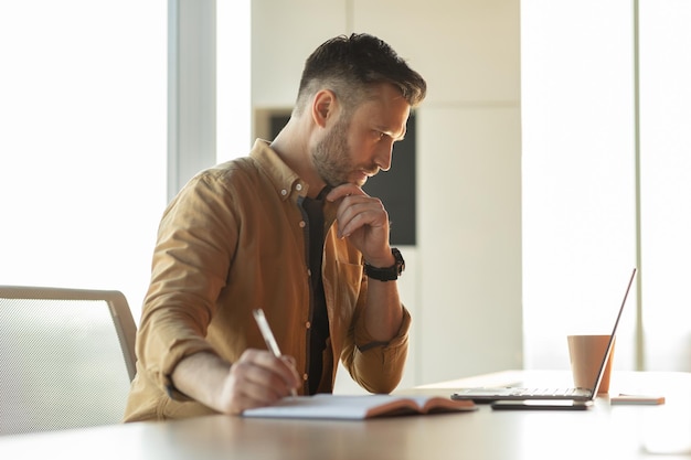 Foto empresário escrevendo tomando notas fazendo relatório de negócios sentado no escritório