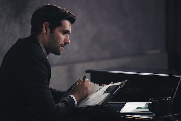 El empresario escribe en un cuaderno mientras está sentado en un escritorio