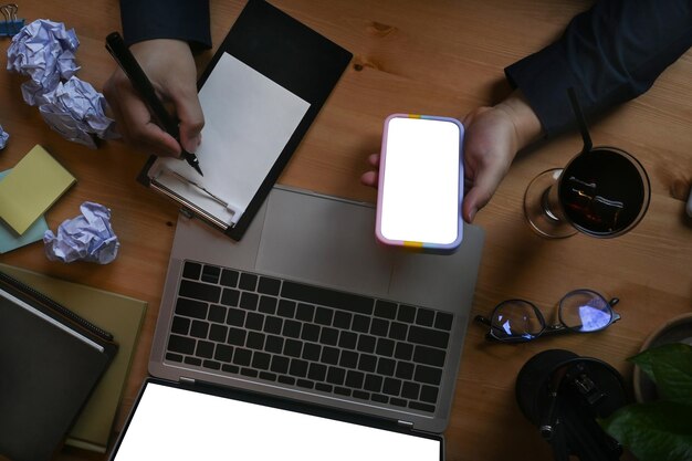 Empresario escribiendo algo en el bloc de notas y usando un teléfono móvil