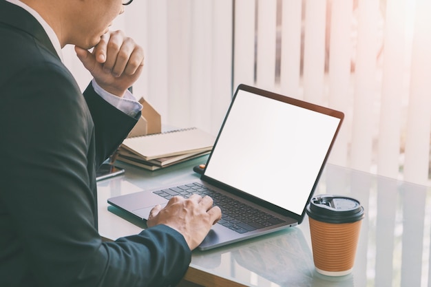 Empresario escribiendo en la computadora portátil con el teléfono inteligente y la taza de café