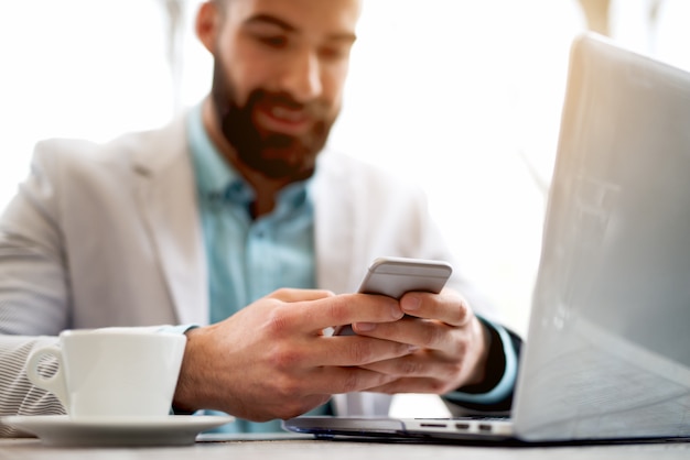 Foto empresario escribiendo mensaje teléfono móvil portátil café bar oficina.