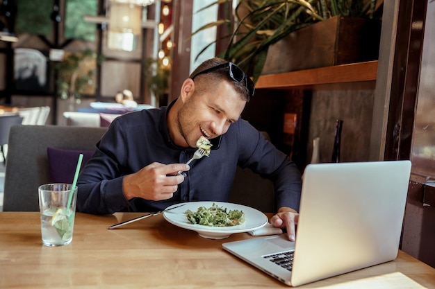 El empresario está almorzando mientras habla por teléfono en el restaurante. trabajo remoto.