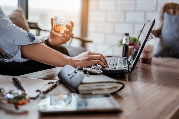 Empresário está experimentando o café que a loja trouxe enquanto trabalhava com o laptop