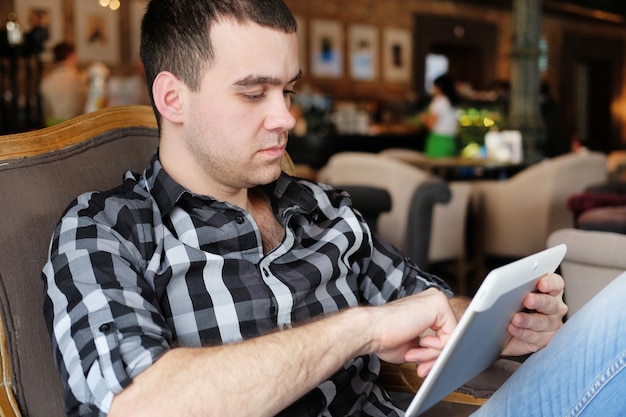 empresário está segurando um tablet digital e sentado em um café.