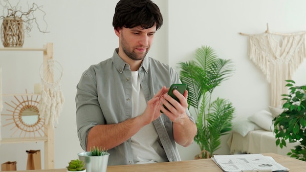 Empresário está usando um smartphone e sorrindo enquanto trabalha no escritório