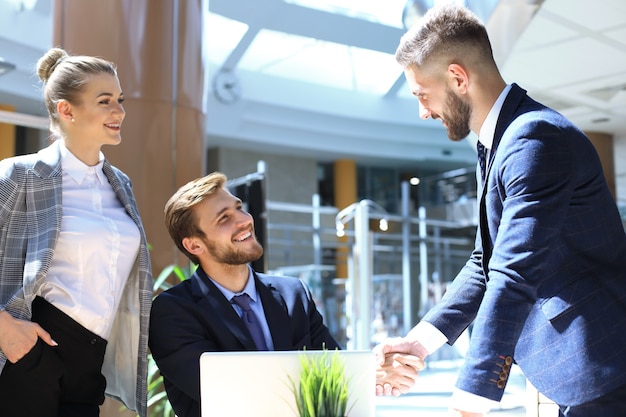 Empresario estrecharme la mano para sellar un trato con su socio y colegas en la oficina.