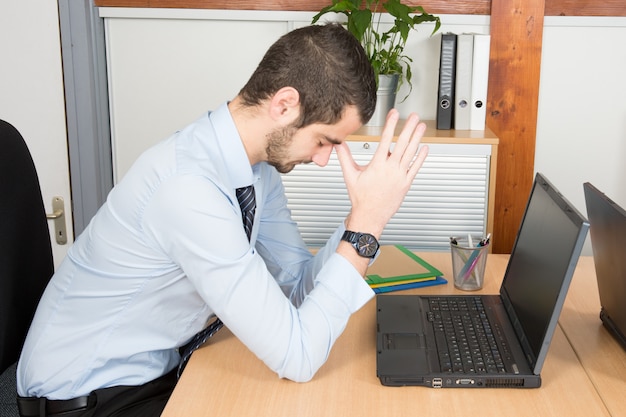 Foto empresario de estrés sentado en el escritorio de oficina con la mano en la cabeza