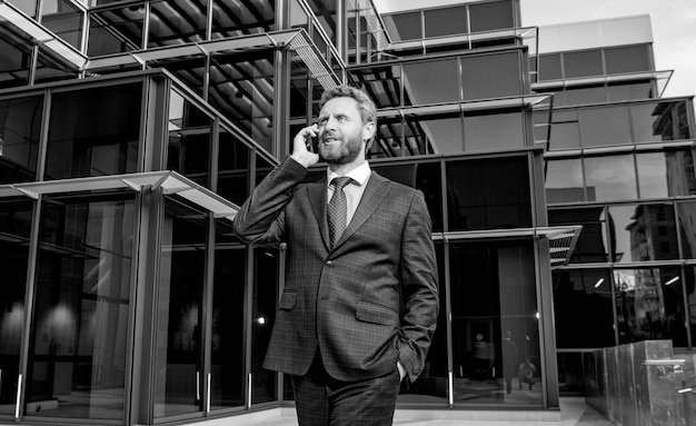 Empresario exitoso en traje profesional tiene conversación telefónica fuera de la conversación de la oficina