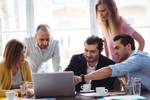 Empresário explicando aos colegas de trabalho usando laptop