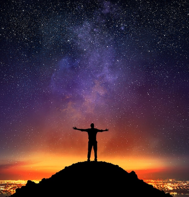 Empresário exulta em uma montanha com céu estrelado