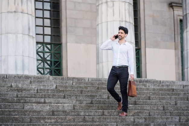 Empresário falando ao telefone em pé na escada ao ar livre. Conceito de negócios.