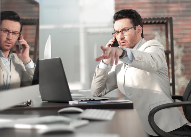 Empresário falando em um telefone celular sentado à mesa do escritório