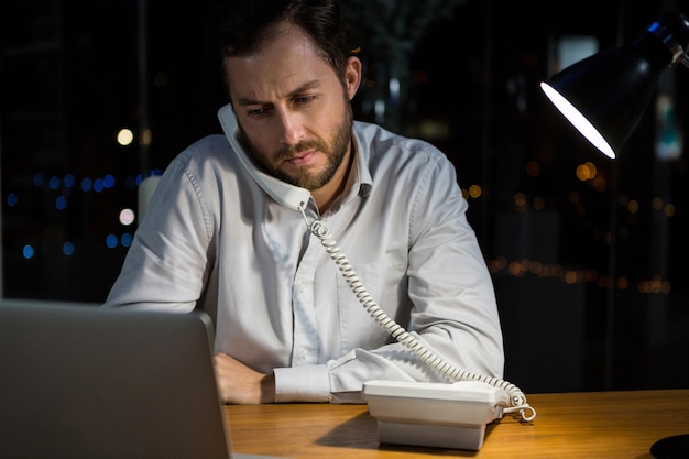 Empresário falando no telefone enquanto trabalhava no escritório