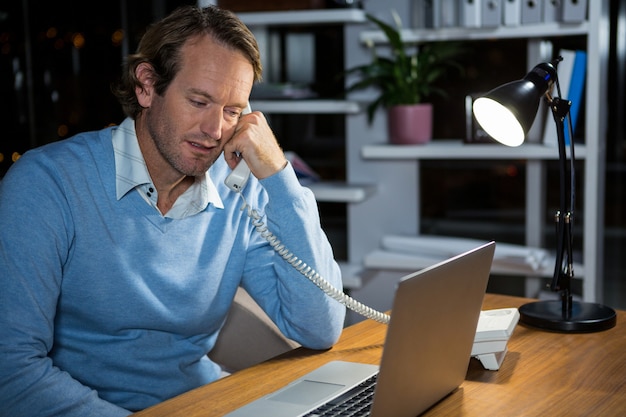 Empresário falando no telefone enquanto trabalhava no escritório