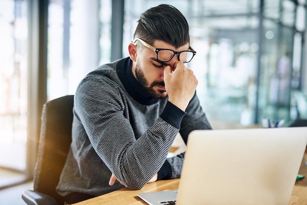 Empresario fatiga ocular y dolor de cabeza con computadora portátil en la oficina con estrés de agotamiento y exceso de trabajo por el escritorio empleado profesional y incomodidad de gafas con plazo de trabajo migraña y frustrado