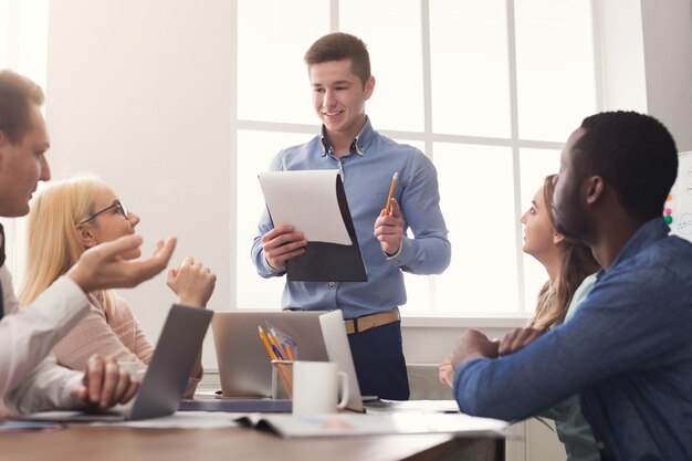 Empresário fazendo apresentação para colegas em um escritório moderno. equipe de jovens negócios discutindo nova estratégia de marketing, planejamento de projeto de inicialização, espaço de cópia