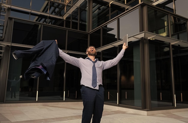 Foto empresario feliz con portátil gritando celebrando el éxito empresarial al aire libre siéntase libre de libertad