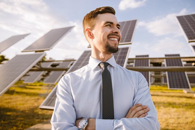 Empresario feliz con ropa formal de pie en el campo de la energía solar